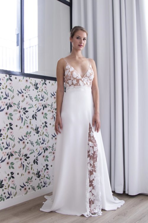 Robe de mariée Lola avec son décolleté triangle et son bas de robe fluide fendu sur la jambe et orné d'une quille en tulle rebrodé.