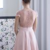 De dos, la robe de soirée rose poudré Jeanelle sublime la cambrure avec ses petits boutons recouverts délicats et sa taille marquée d'une ceinture a trois plis.